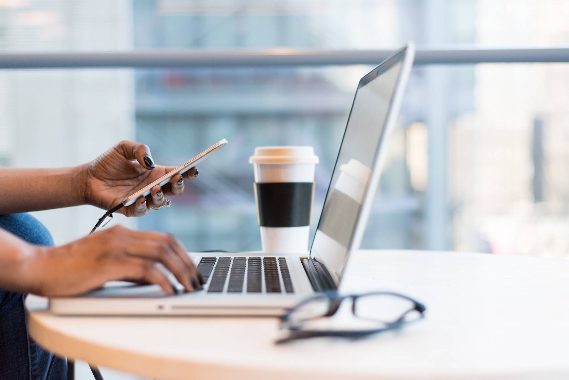 black female remote worker on phone and laptop at desk