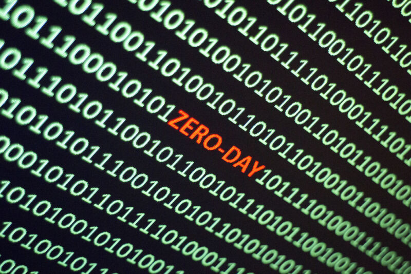 The word ZERO-DAY is hidden amidst a screen filled with ones and zeroes.