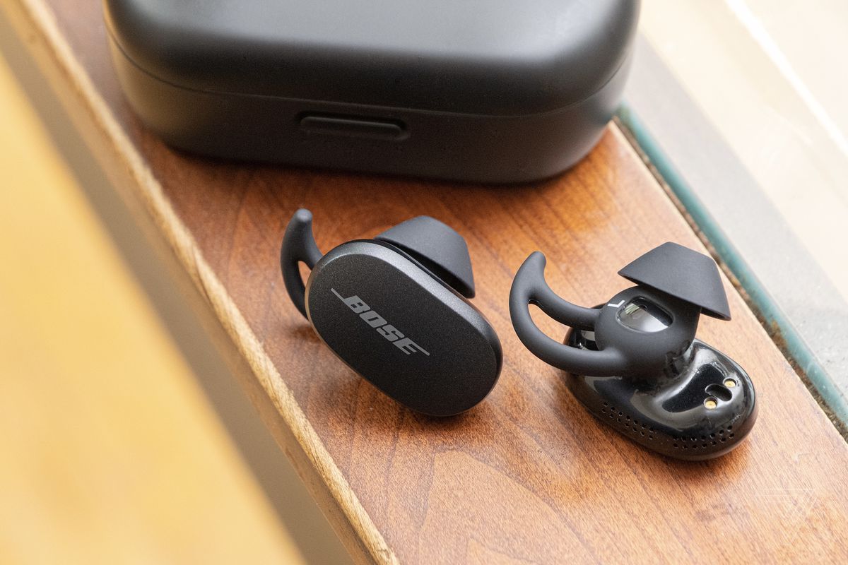The Bose QuietComfort Earbuds on a table beside the carrying case.