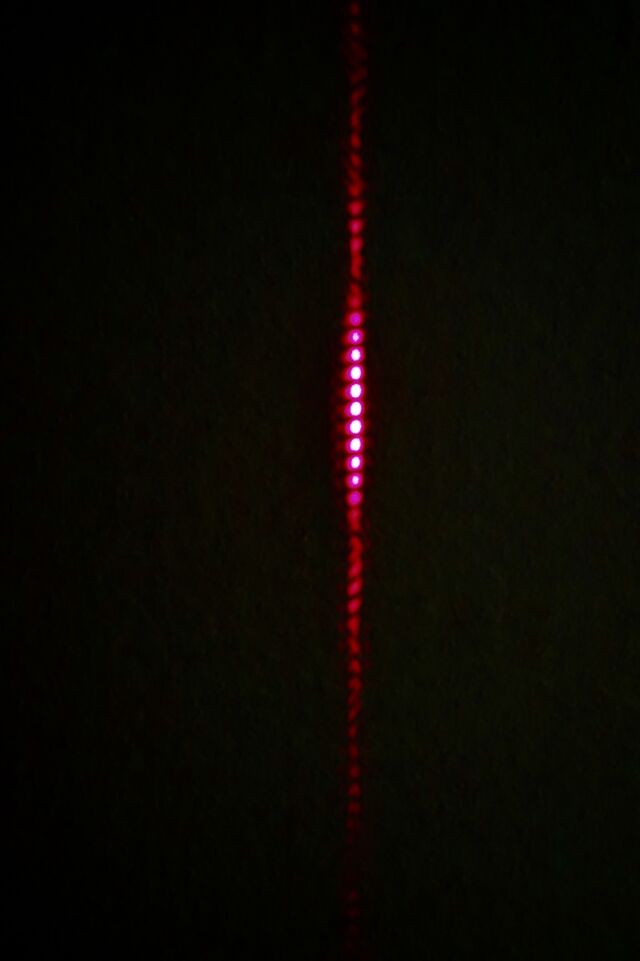 Laser light passing through the two horizontal slits produces the distinctive stripes of quantum mechanics.