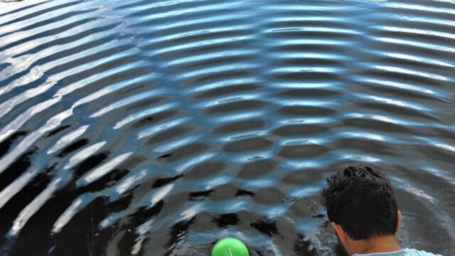 Water waves from two sources (one visible in green, the other hidden behind the presenter). The circular waves overlap into regions of extra strength (bright stripes) and regions where the waves cancel each other out (dark bands). The formation of stripes is a signature of wave motion. 