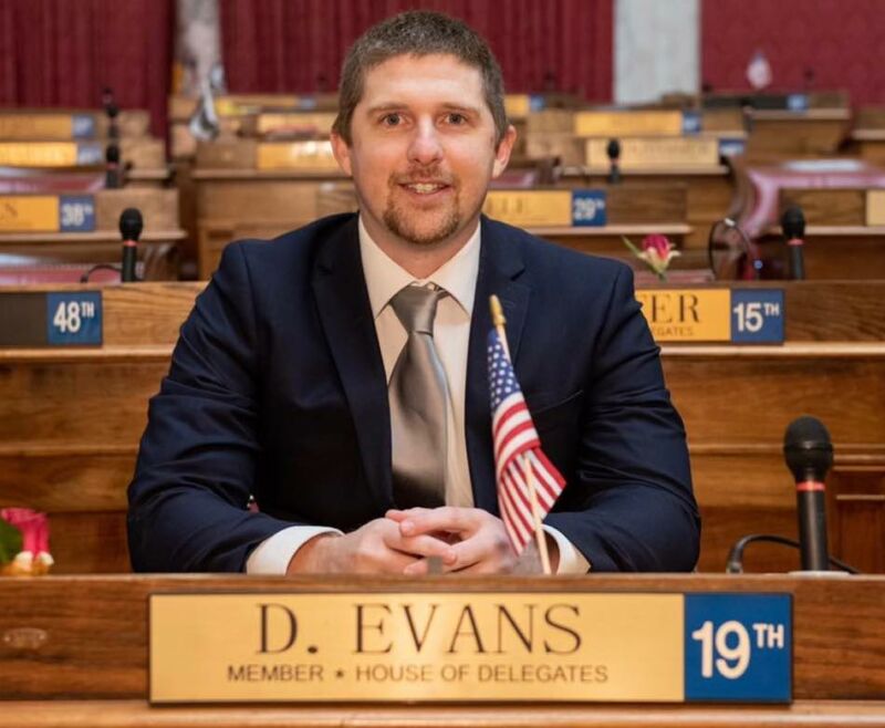 Derrick Evans sitting in the West Virginia House of Delegates, with a small American flag propped up in front of him.