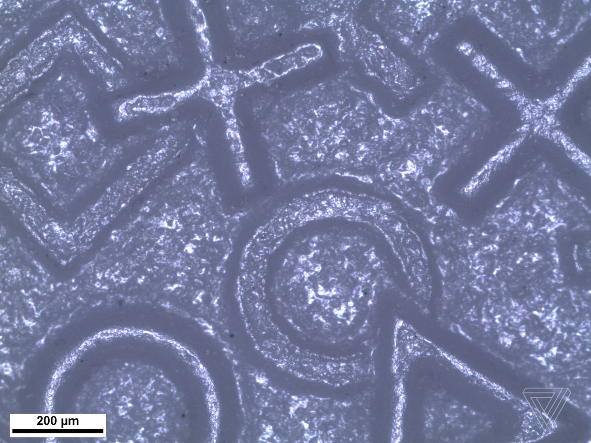 A microscope photo of the DualShock 4’s texture shows overlapping square, triangle, circle and cross symbols