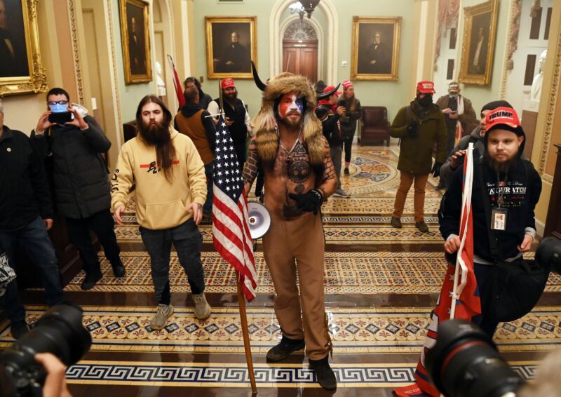 Supporters of former President Donald Trump, including Jake Angeli, a QAnon supporter known for his painted face and horned hat, enter the US Capitol on January 6.